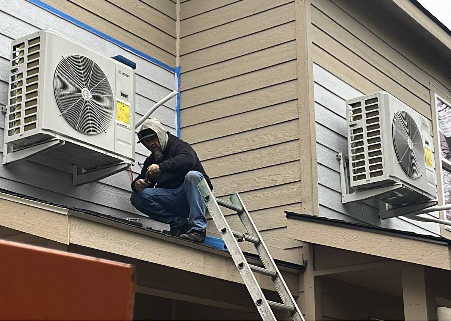 HVAC technician installing Bosch mini-split outdoor units on second story residential building in Yakima WA